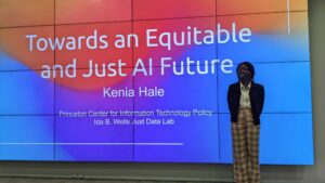 Scholar Kenia Hale stands on stage in front of her presentation in Doha, Qatar