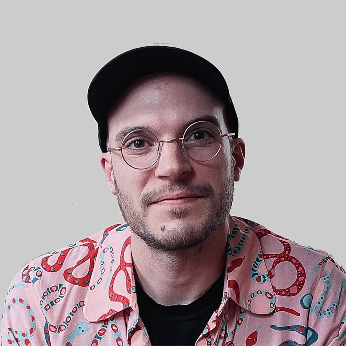 A headshot of a person wearing a baseball cap and a pink shirt with various colors.